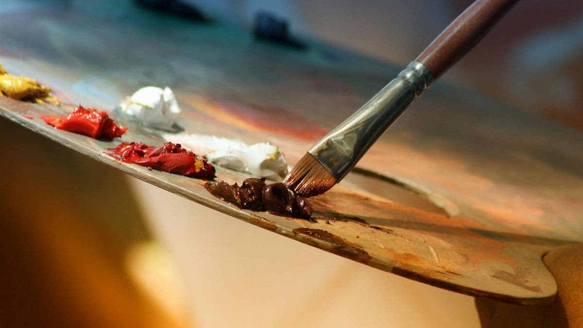 Vibrant artist palette with paint and brush creating colorful artwork.