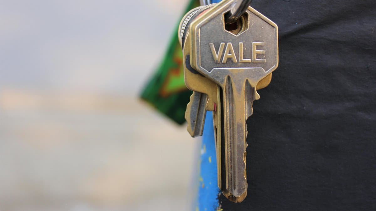 A detailed view of a metallic key with 'Vale' engraved on it, hanging against a blurred background.