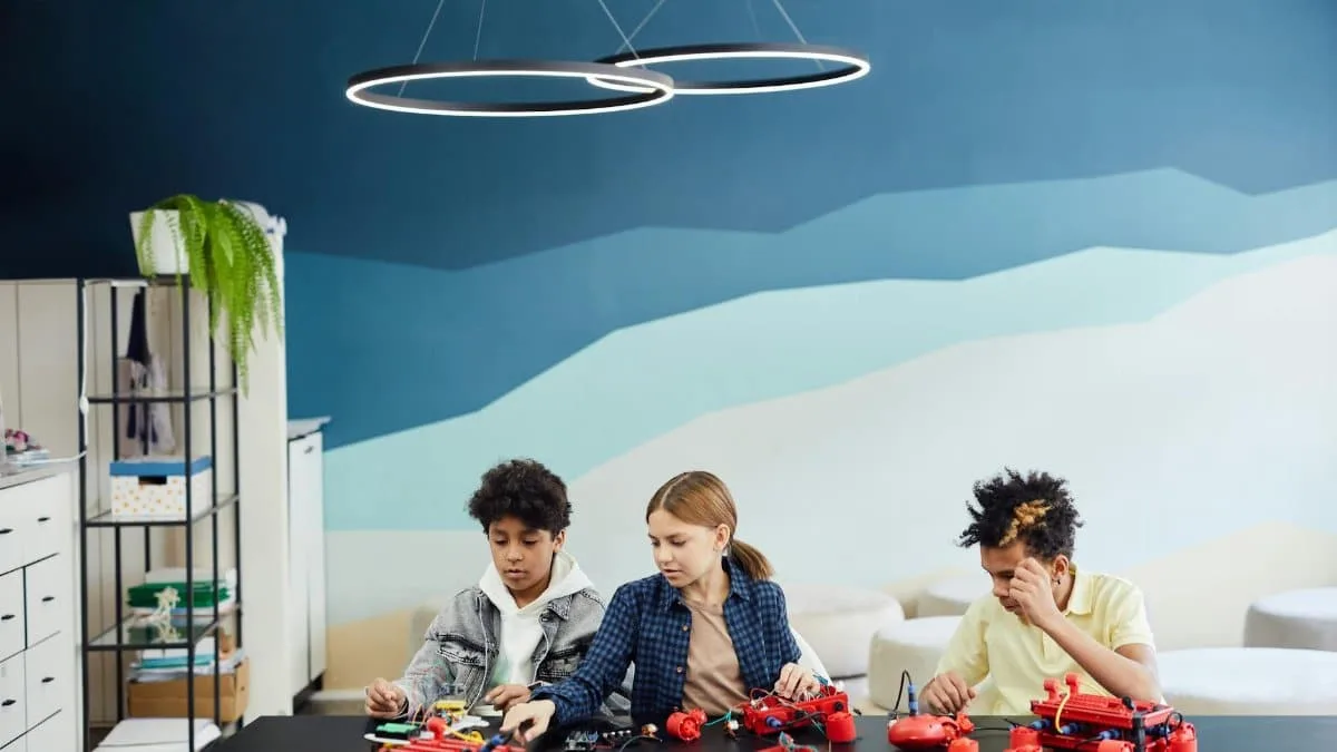 Three children work on robotics at a table indoors, showcasing teamwork and technology learning.