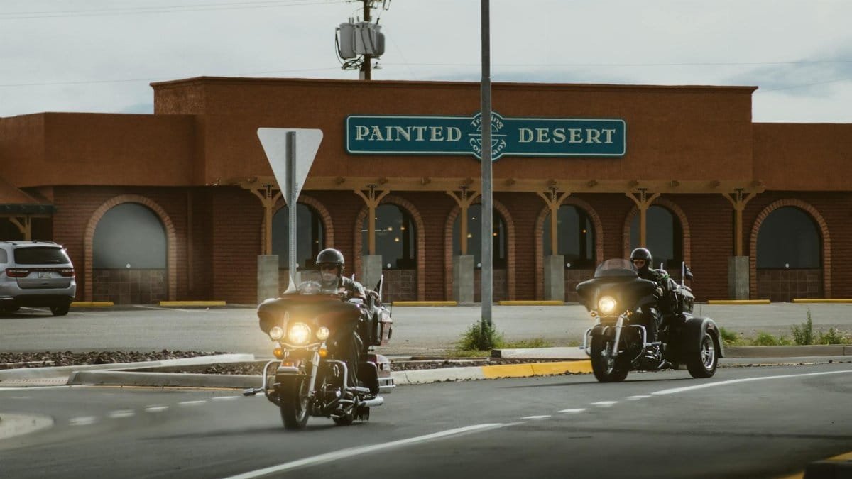 Bikers on a road trip riding through Young, Arizona past the Painted Desert building.