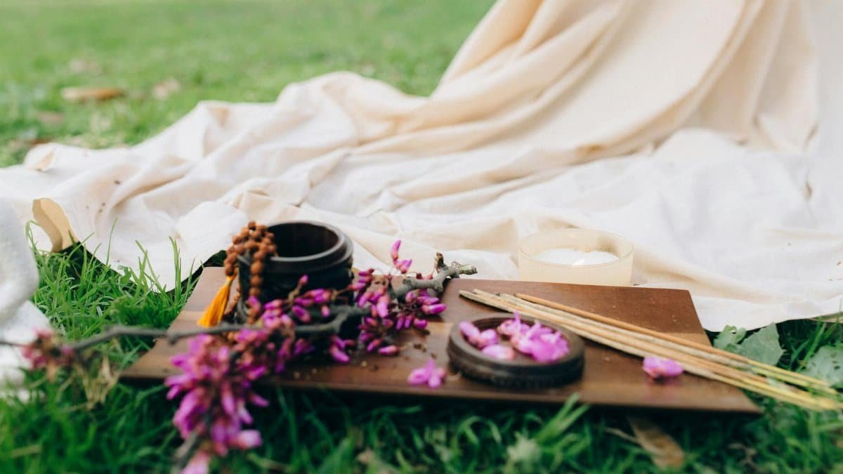 A tranquil outdoor setting featuring flowers, incense sticks, and white fabric for a calming aromatherapy experience.