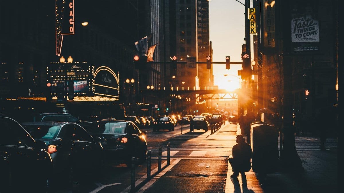 Moody downtown Chicago street at sunset with cars and glowing lights.