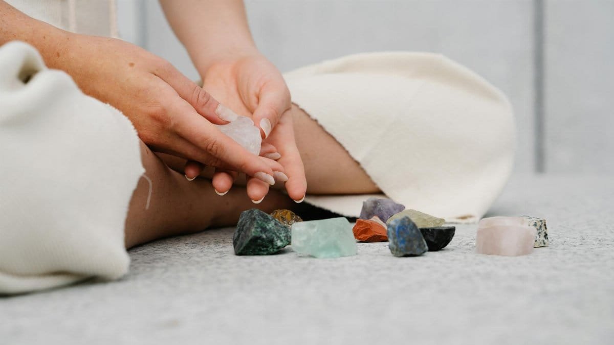 Close-up of hands holding healing crystals on a soft surface indoors, symbolizing spirituality and mindfulness.