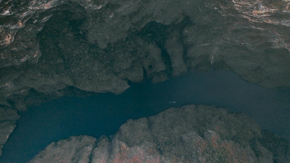 Explore this stunning aerial shot of a rocky cave with deep blue water, showcasing nature's beauty.