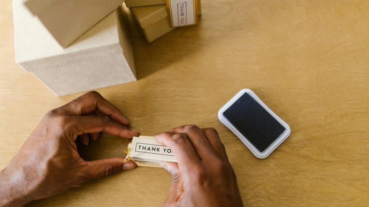 Hands of a small business owner sealing thank you cards with an ink pad.