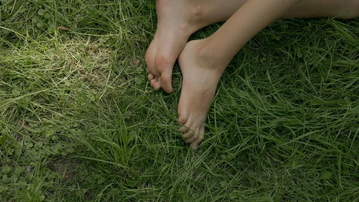 Close-up of bare feet relaxing on lush green grass, depicting tranquility.