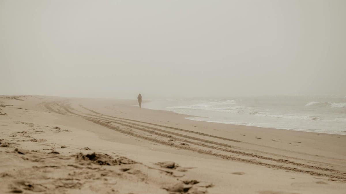 A lone silhouette walks on a foggy beach in Lincoln City, Oregon, USA.