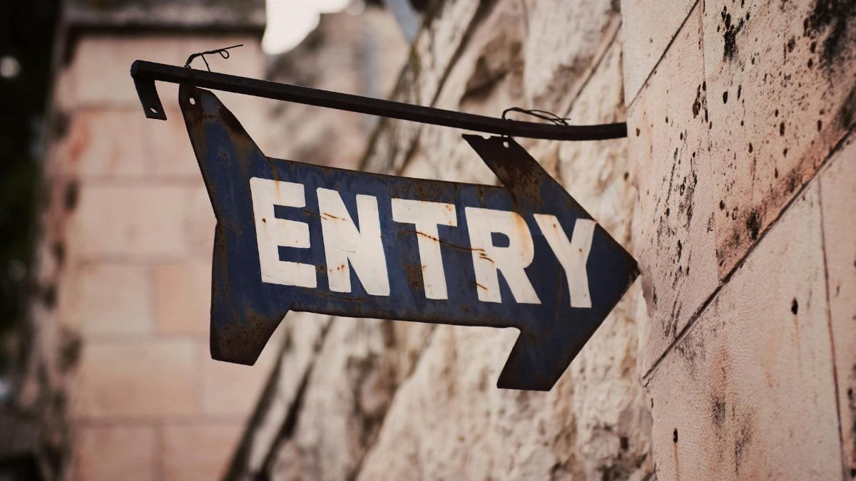 An old metal ENTRY sign with arrow on a stone wall in Jerusalem, Israel.