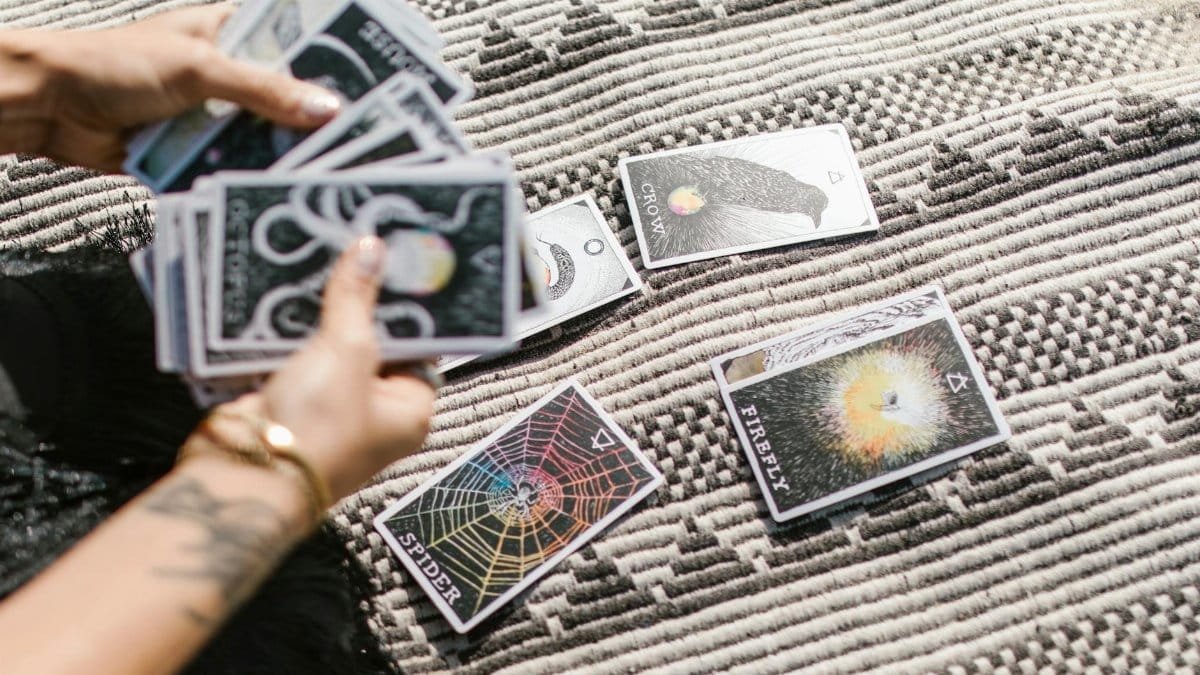 Hands dealing tarot cards for a reading on a stylish geometric rug.