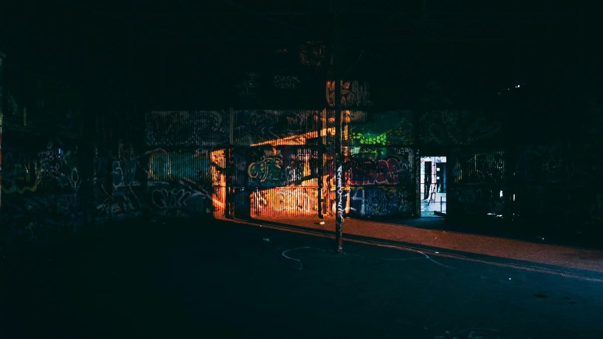 Dark urban interior featuring vibrant graffiti and dramatic lighting in a deserted Dallas warehouse.
