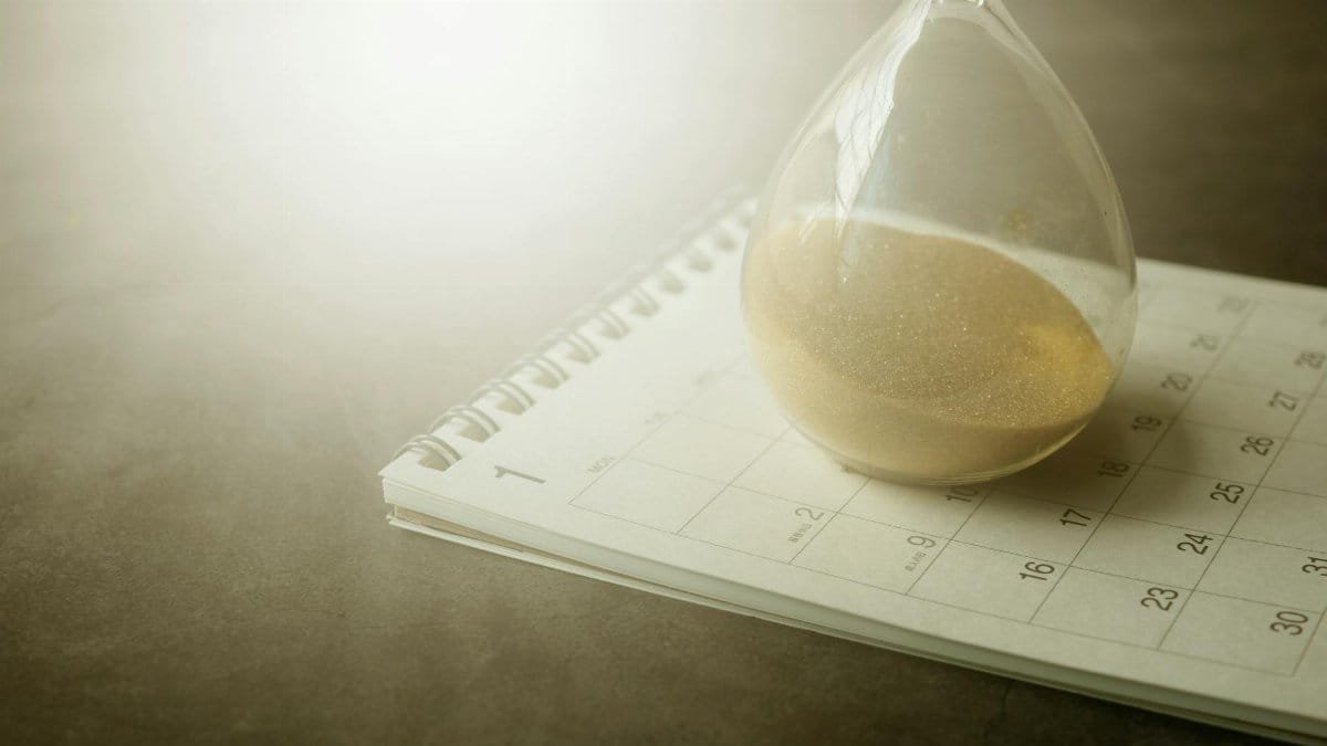 An hourglass on a calendar captures the essence of time management and urgency.
