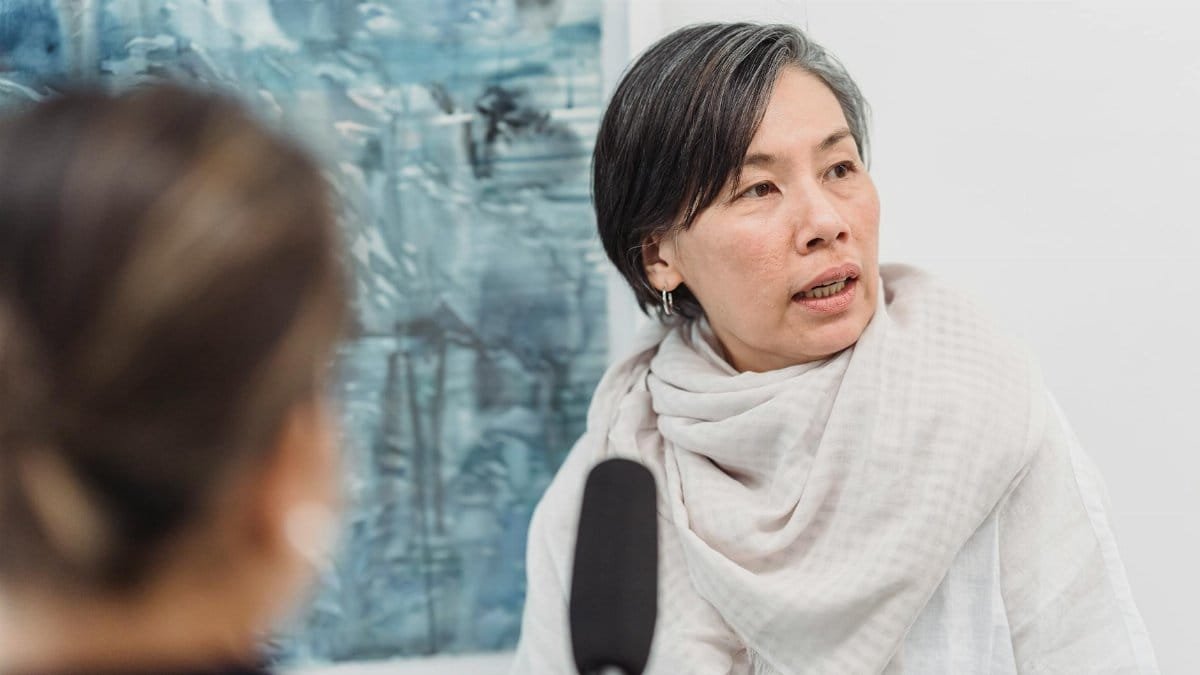 A woman discusses art while being interviewed in a gallery, highlighting culture.
