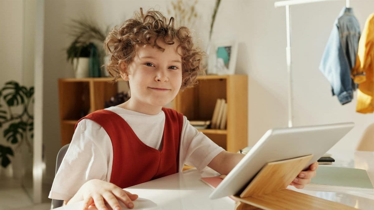 Cheerful child enjoying distance learning with tablet indoors.