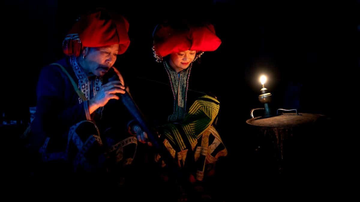 A couple in traditional clothes illuminated by lamp, showcasing cultural heritage and intimacy.