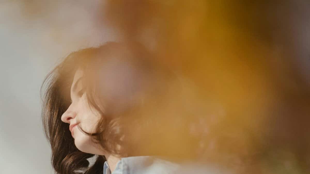 Elegant profile portrait of a young woman in soft lighting with a bob haircut.