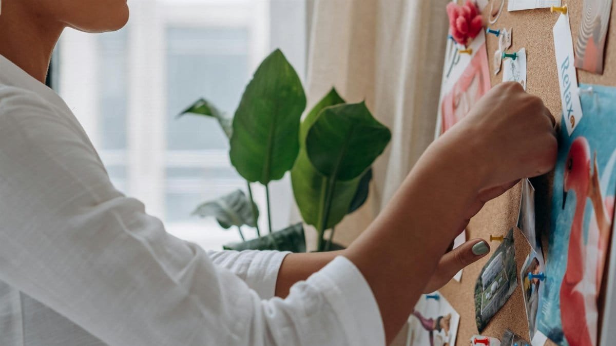 Close-up of a fashion designer arranging photos on an inspiration board indoors.