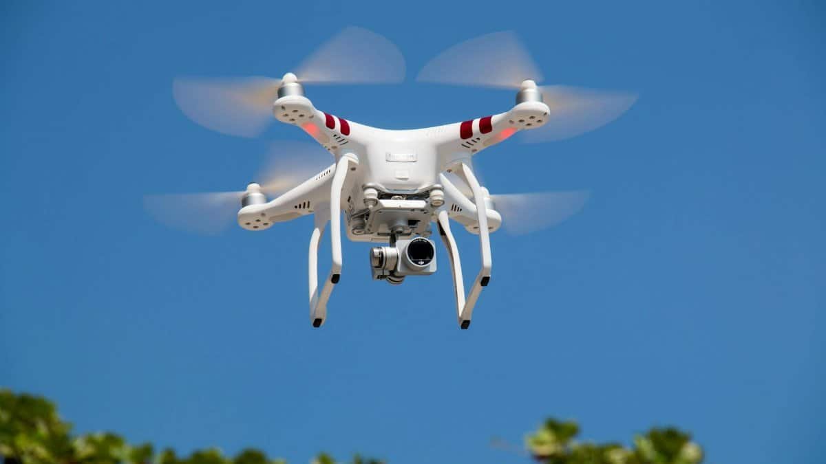 A white drone flying with camera against a clear blue sky in La Libertad.