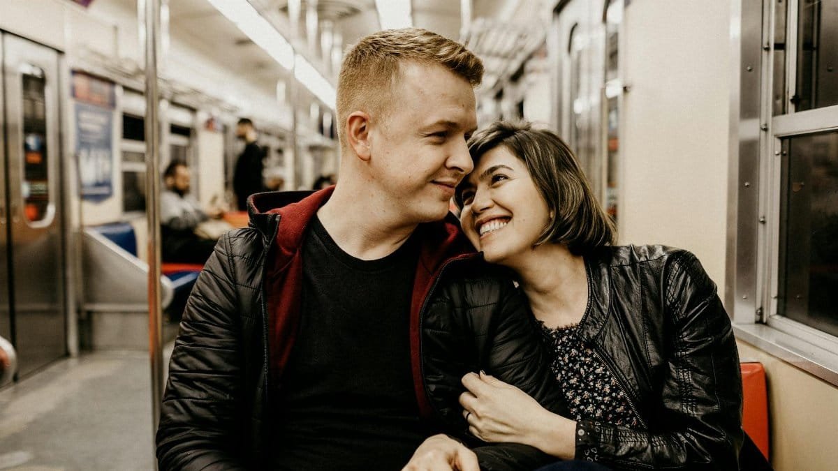 Young couple sharing a tender moment together on a train journey.