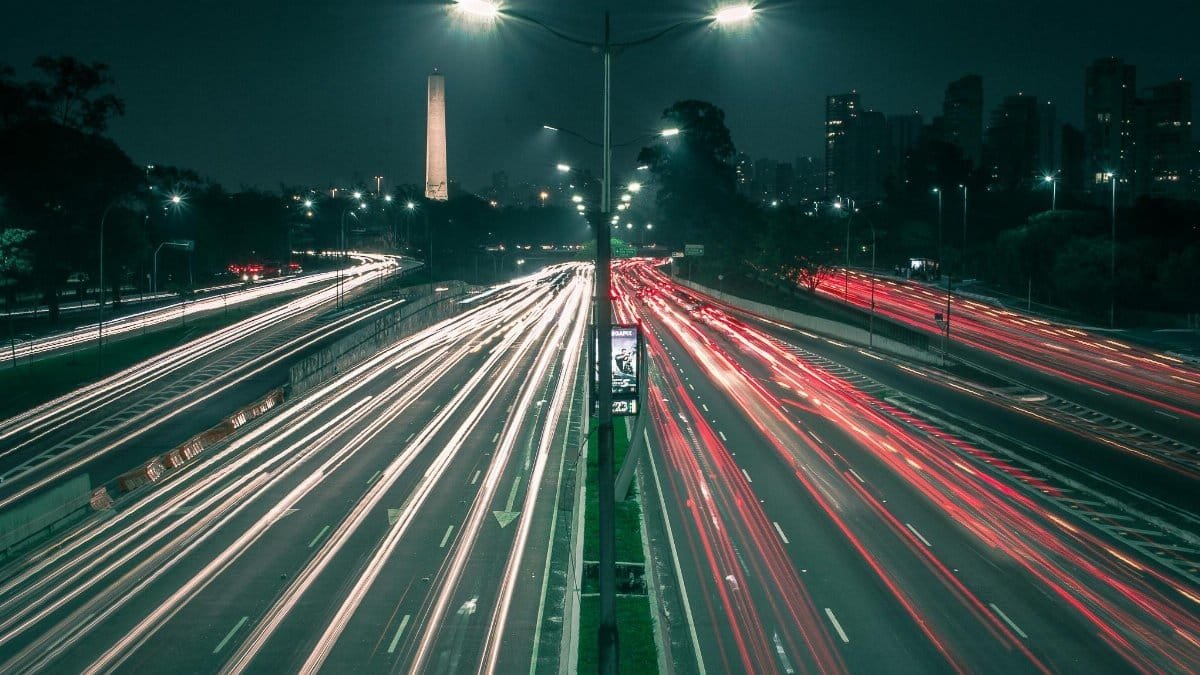A bustling night shot of São Paulo's expressway with vibrant light trails and city skyline.