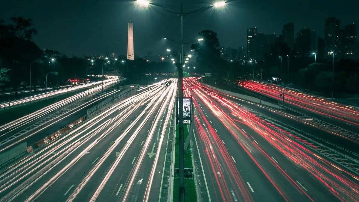 A bustling night shot of São Paulo's expressway with vibrant light trails and city skyline.