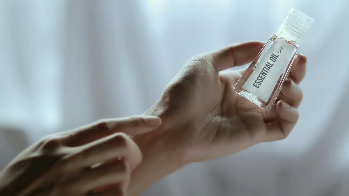 Close-up of a hand holding an essential oil bottle, ideal for wellness and skincare concepts.