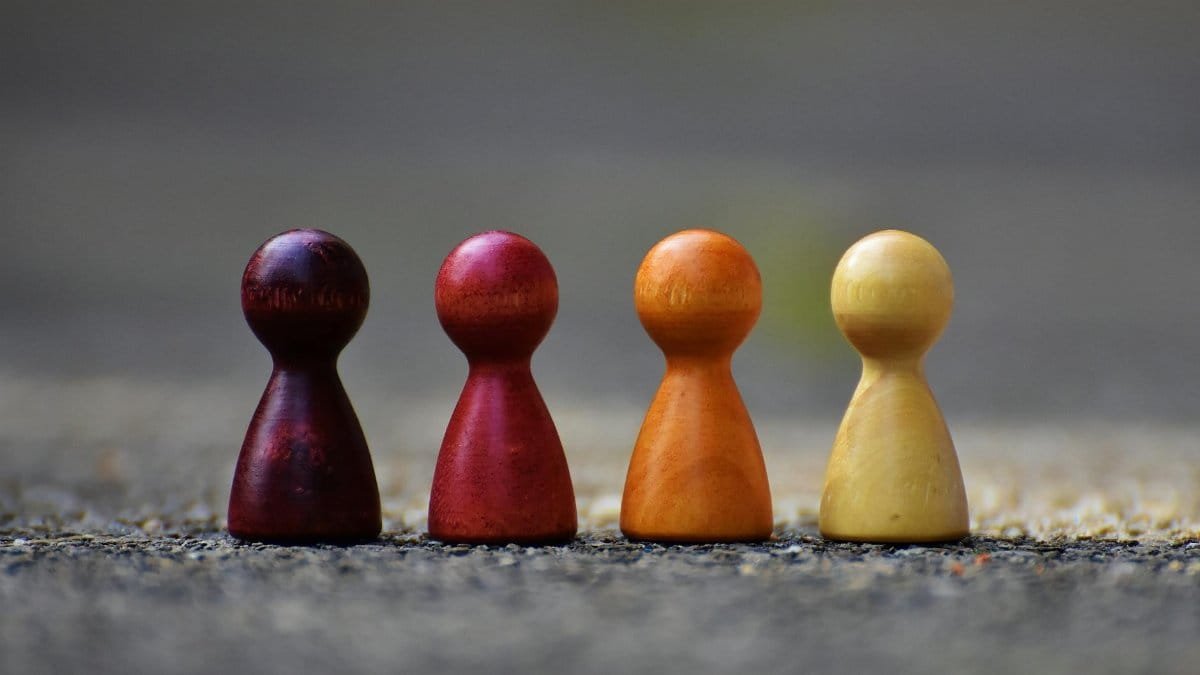 Close-up of four colorful wooden pawn pieces arranged in a row.