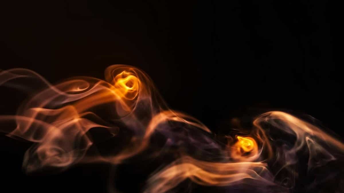 Abstract image capturing the swirling motion of fire and smoke against a dark background.