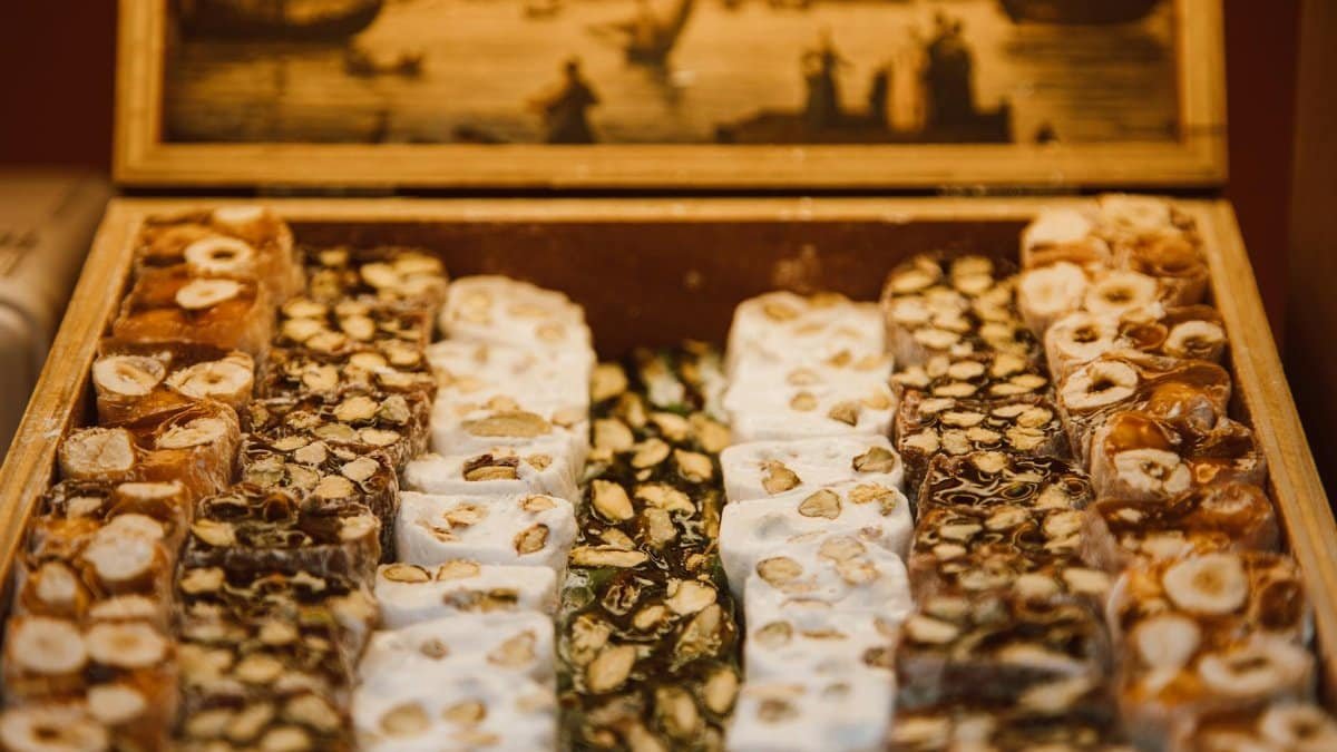 A variety of nougat flavors beautifully arranged in a rustic wooden box, perfect for dessert enthusiasts.