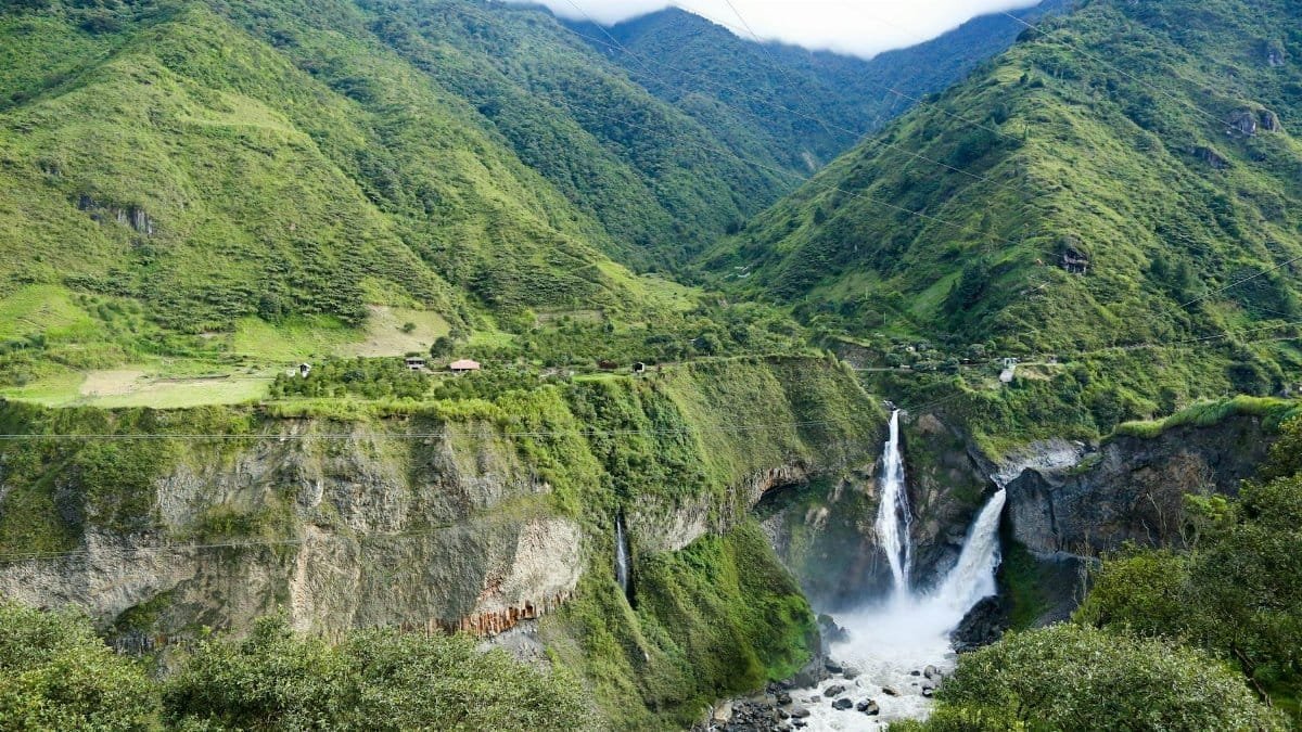 Stunning waterfall cascading in a lush Ecuadorian valley, surrounded by green mountains.