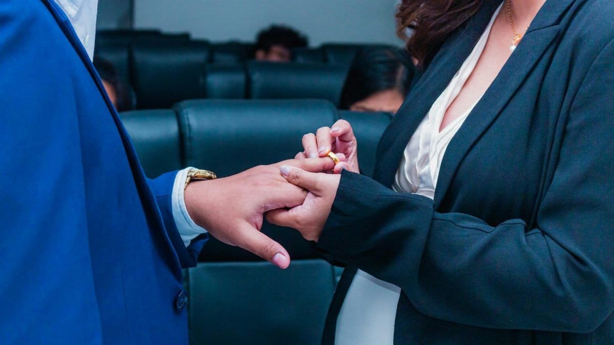 A close-up of two people exchanging rings, symbolizing commitment in an office setting.