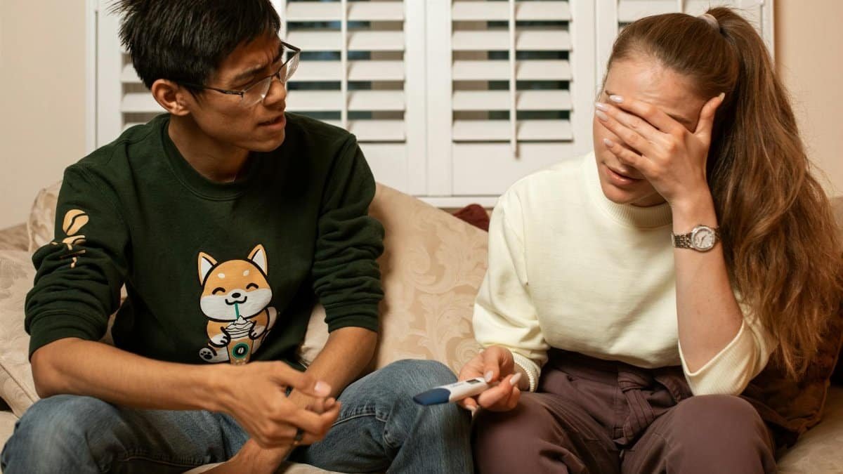 A couple on a sofa sharing an emotional moment with a pregnancy test.