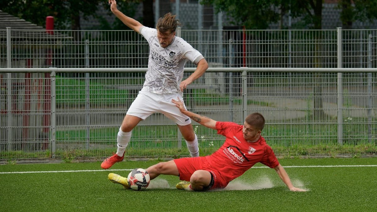 Two male soccer players in action, tackling for the ball during a match.