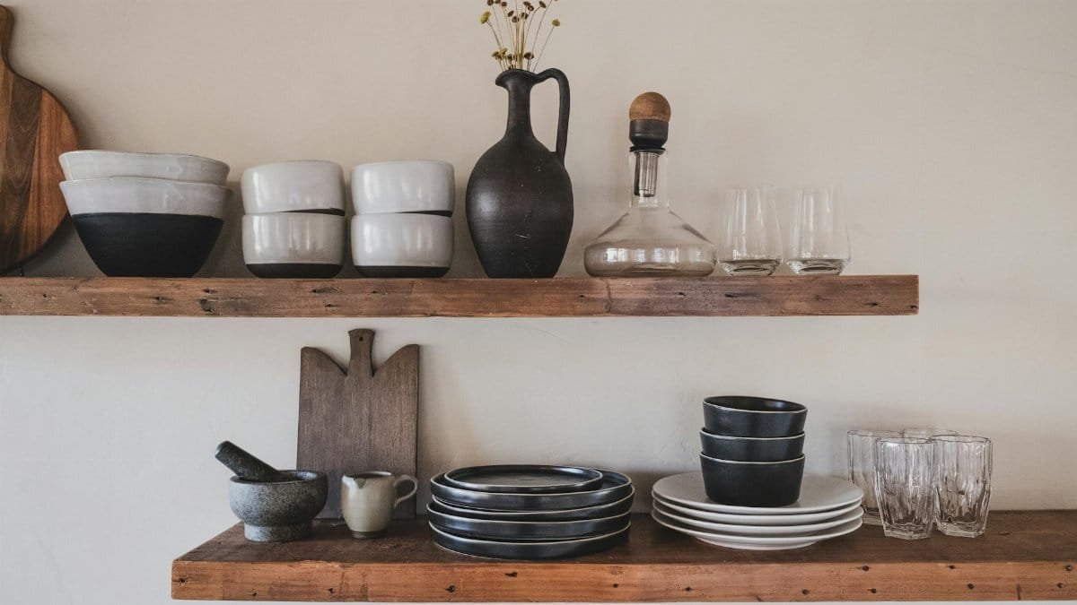 Stylish arrangement of ceramic bowls and glassware on rustic wooden shelves.