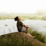 Woman enjoying a peaceful moment by the riverside, embracing nature's serenity.