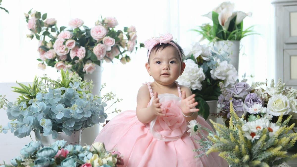 Cute baby surrounded by vibrant floral arrangements, exuding joy and innocence.