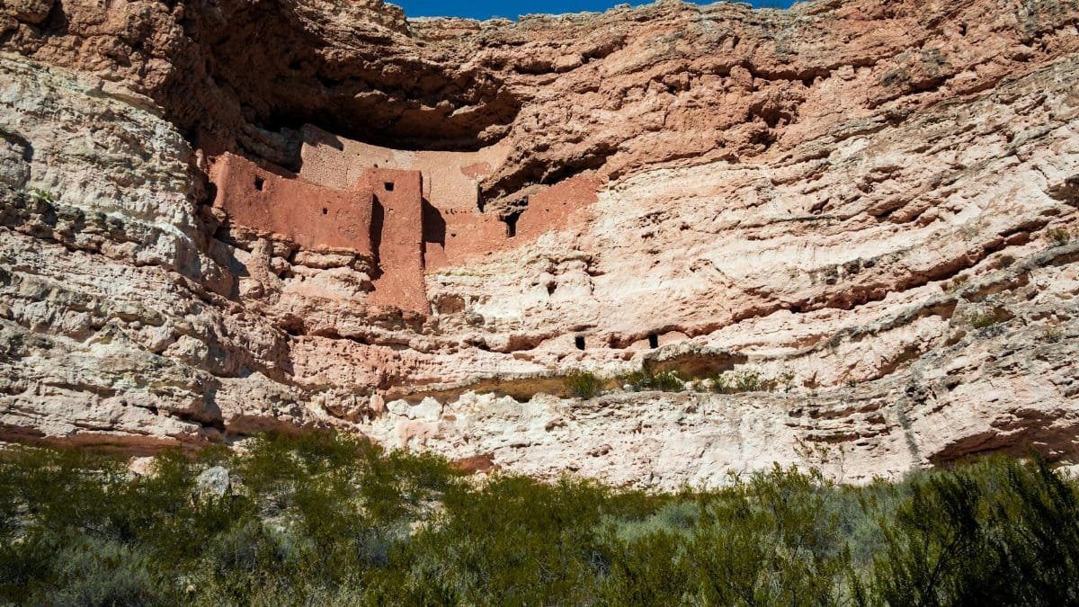 Explore the ancient Montezuma Castle nestled in the red cliffs of Arizona's desert landscape.