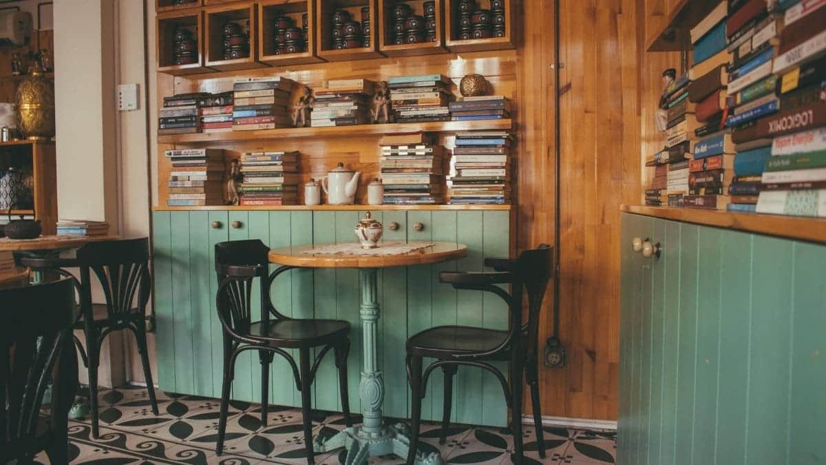 Warm and inviting cafe interior featuring wooden bookshelves and teal decor. Perfect reading nook.