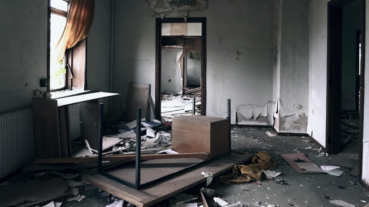 A devastated room showing signs of destruction and neglect, filled with debris and overturned furniture.