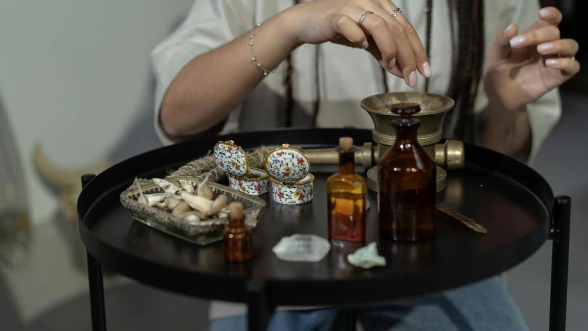 A hand engaging in a spiritual ritual with herbs and bottles on a mystical table.