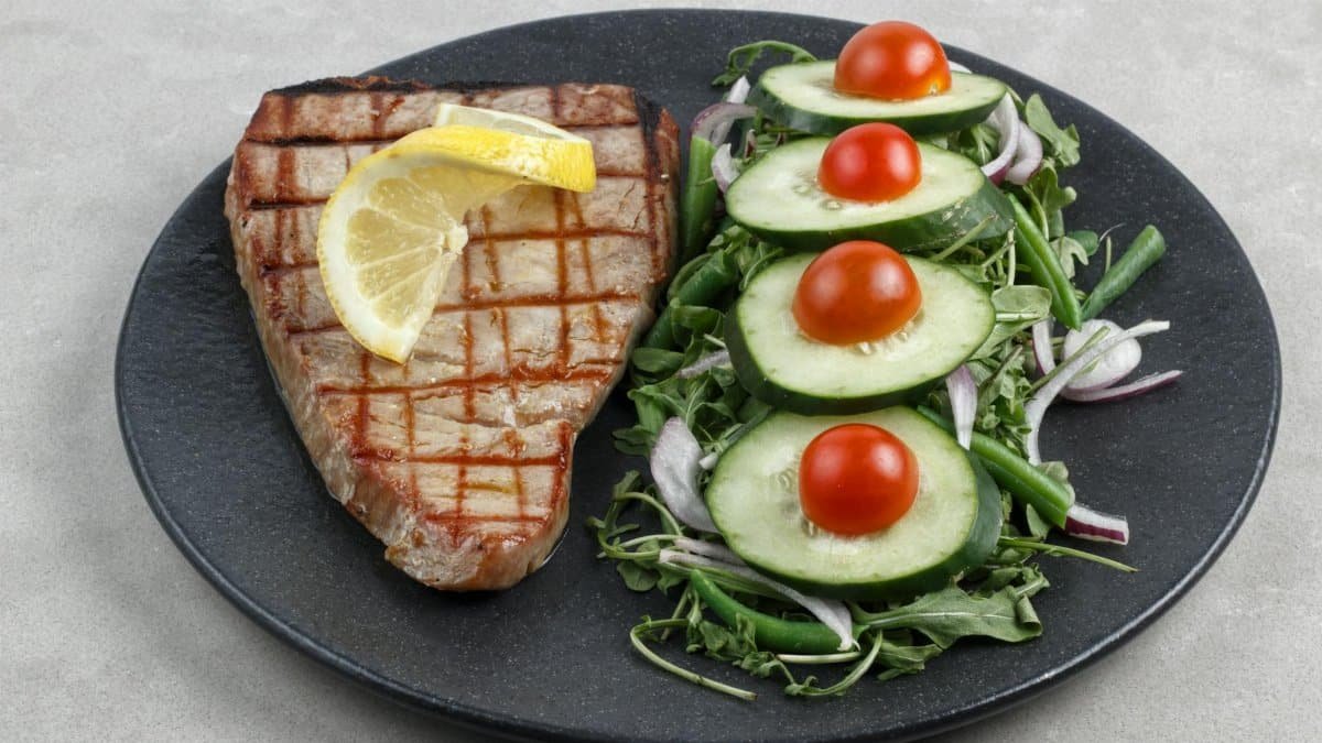 Delicious grilled tuna steak served with fresh cucumber and cherry tomato salad. Perfect for healthy eating.