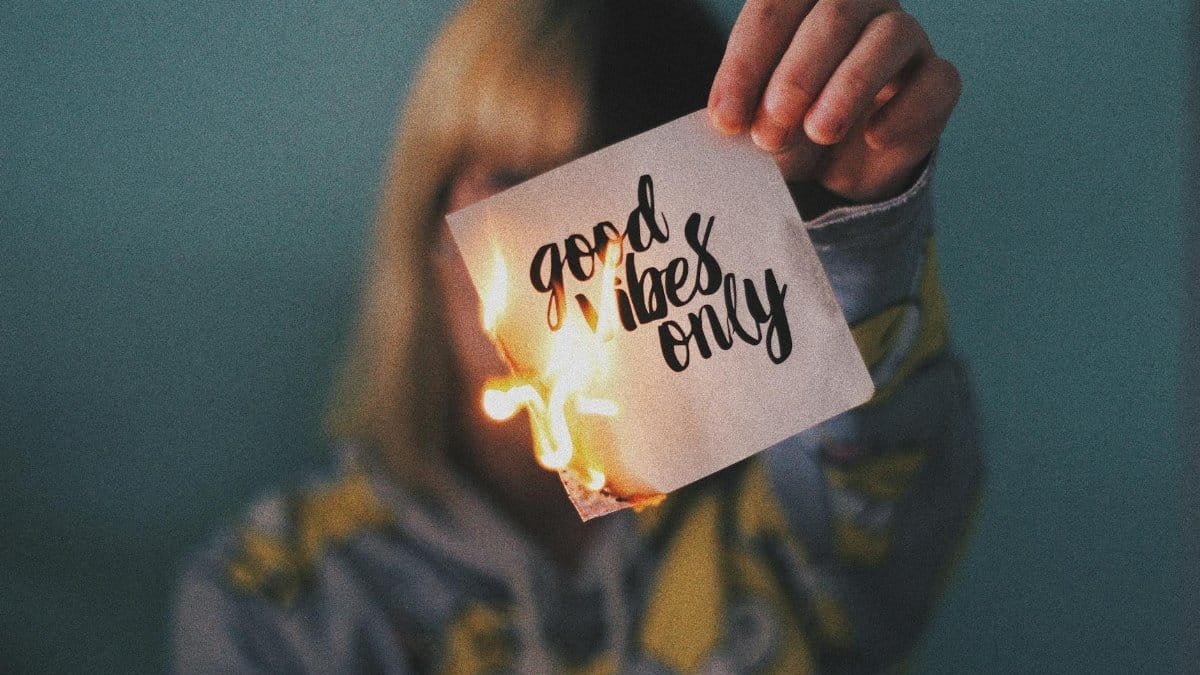 Unrecognizable female showing burning paper with written inscription and bright flame on blurred background
