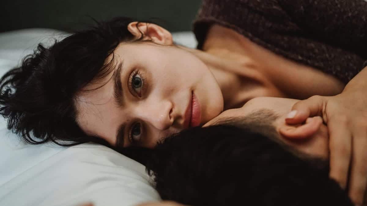 A couple lying closely on a bed, expressing intimacy and connection.