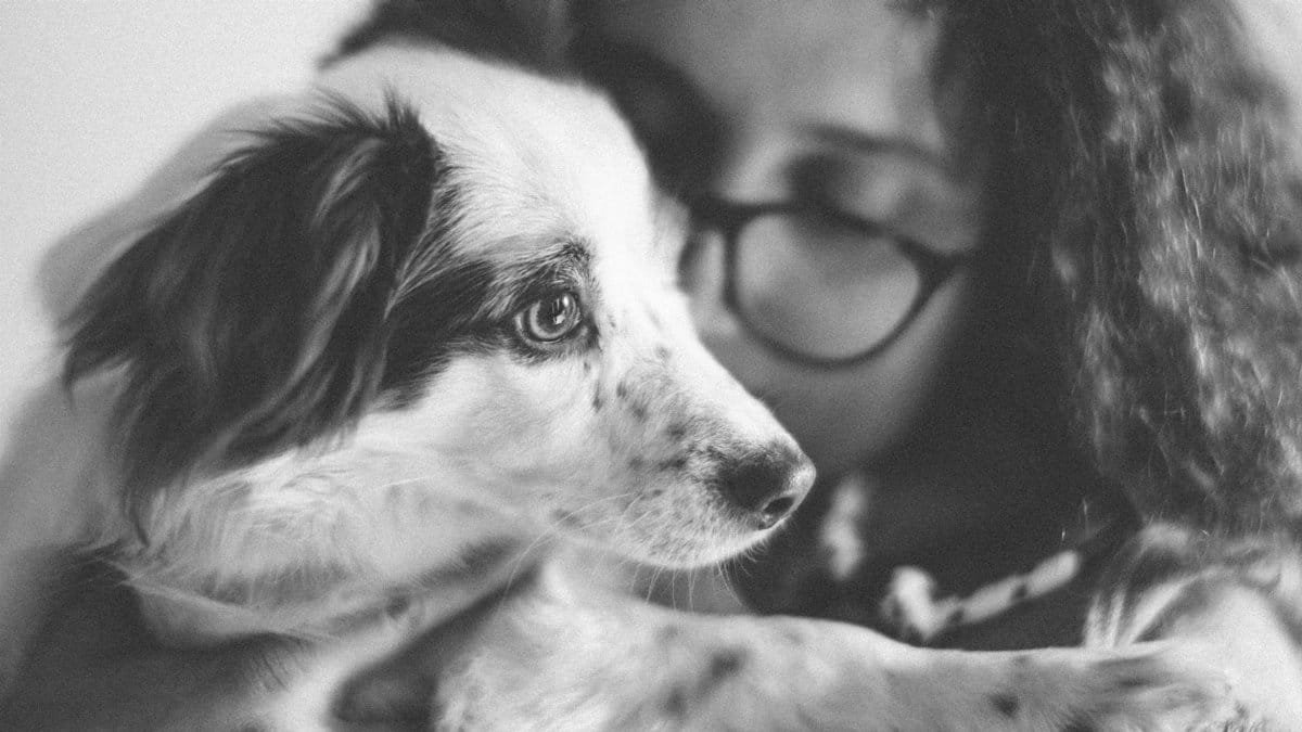 A touching black and white portrait of a girl lovingly hugging her dog.