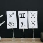 Minimalist decor showcasing zodiac signs with modern elements on a wooden table.