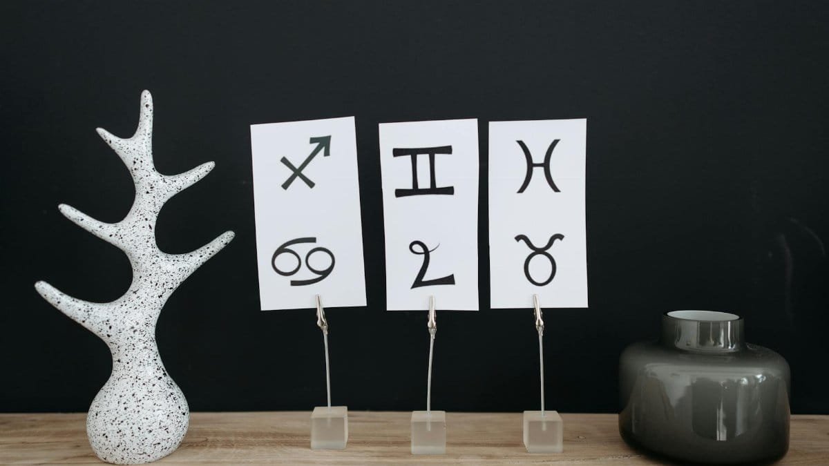 Minimalist decor showcasing zodiac signs with modern elements on a wooden table.