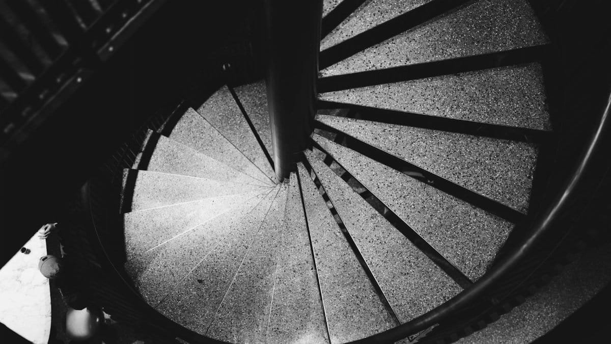 Artistic black and white photo of a spiral staircase viewed from above, showcasing elegant design.