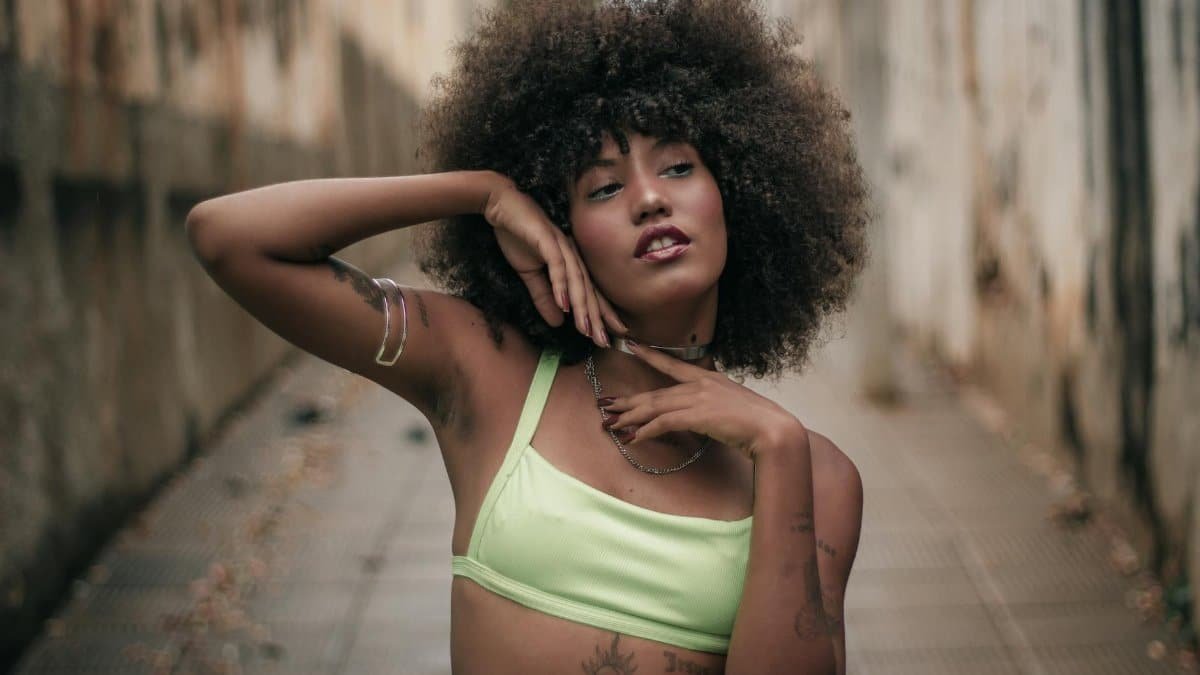 A woman posing confidently in a Barreiras alley, showcasing fashion and a distinctive hairstyle.