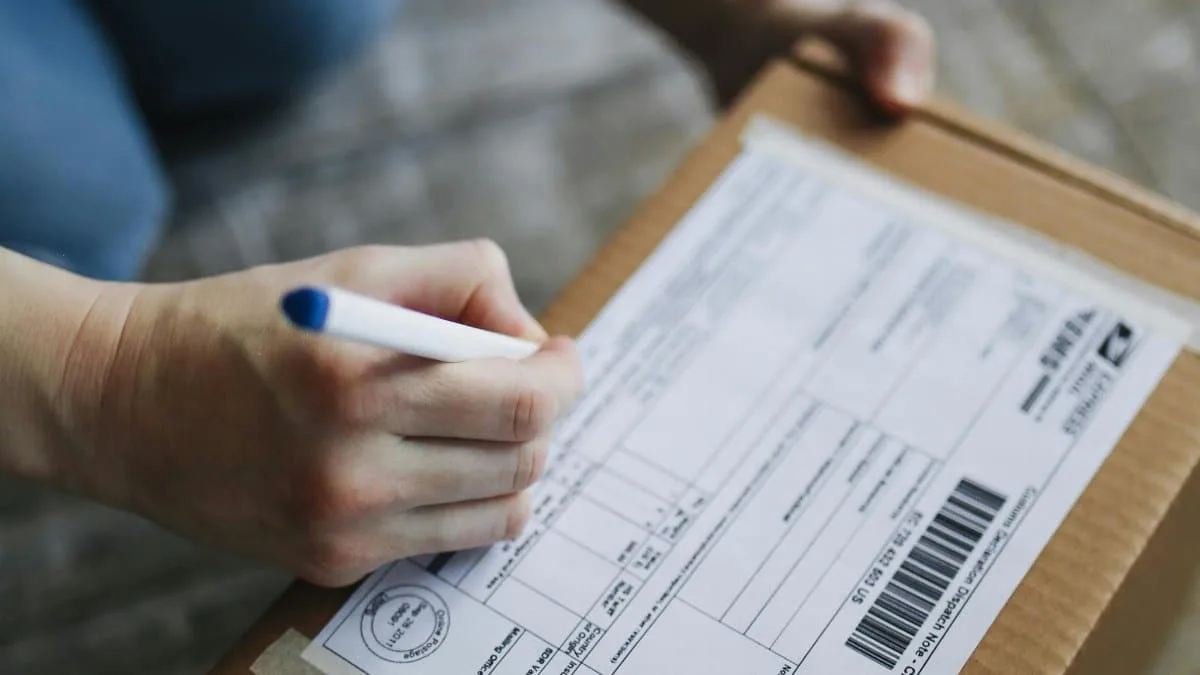 Close-up view of hands writing on a shipping box indoors.