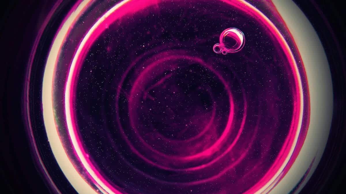 Vibrant abstract pink bubbles forming a circular pattern against a dark background, creating a cosmic feel.