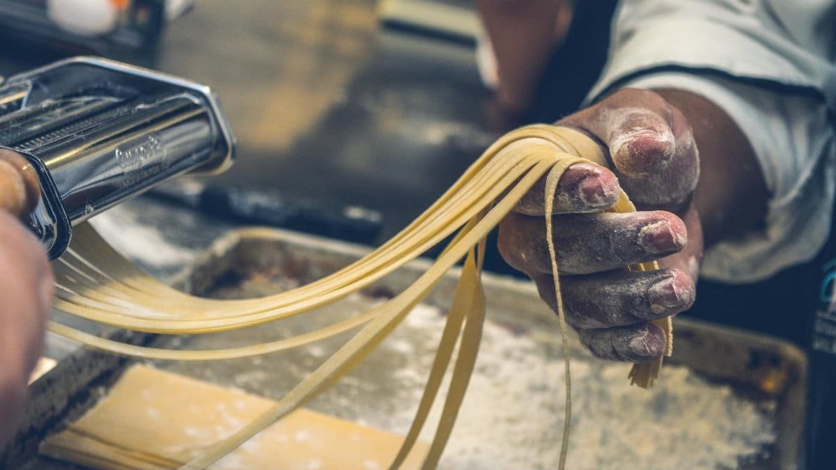 Close-up of hands making fresh pasta, showcasing artisanal techniques and ingredients.